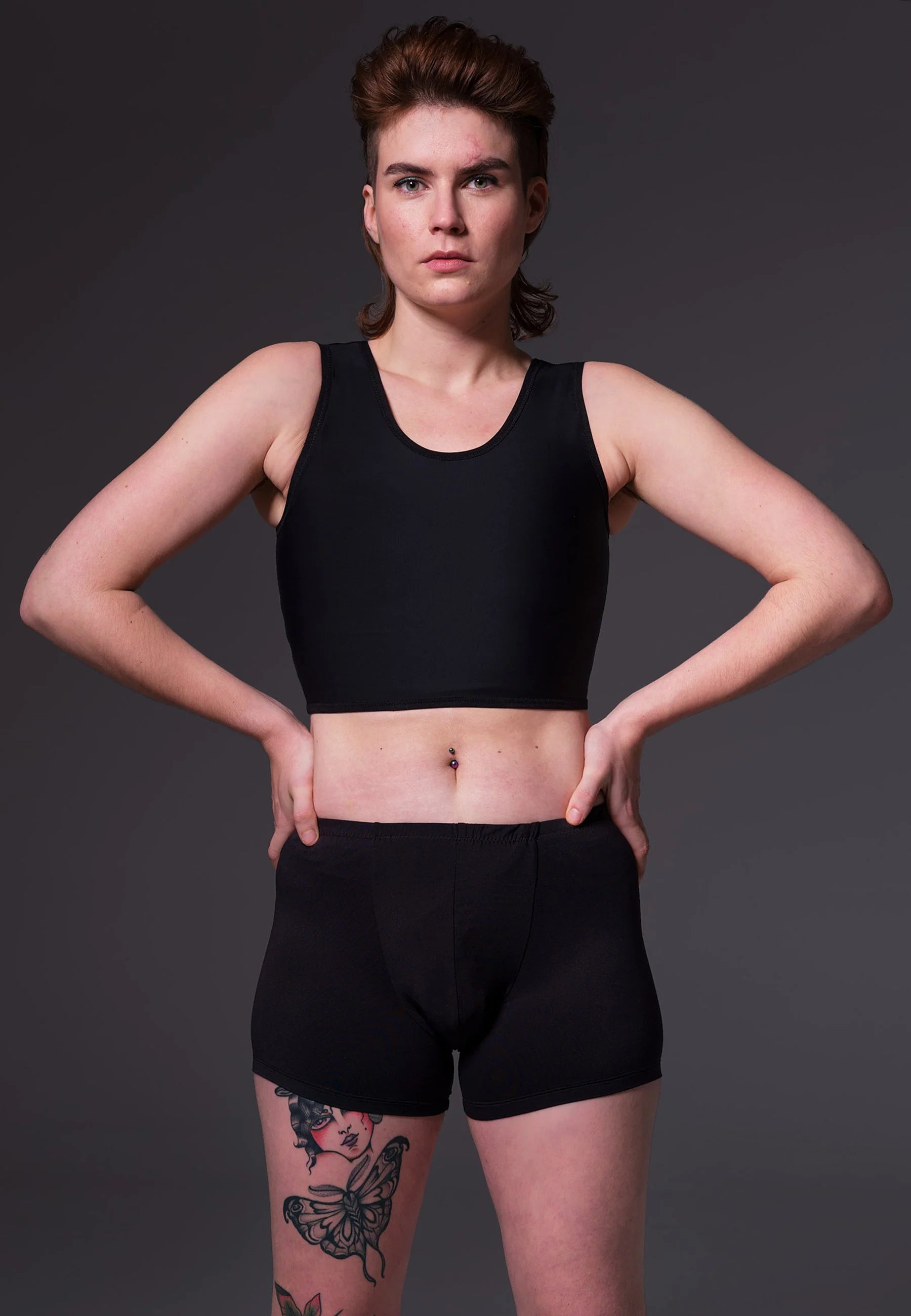 A short black compression chest binder with a soft round neckline and smooth seam free appearance.