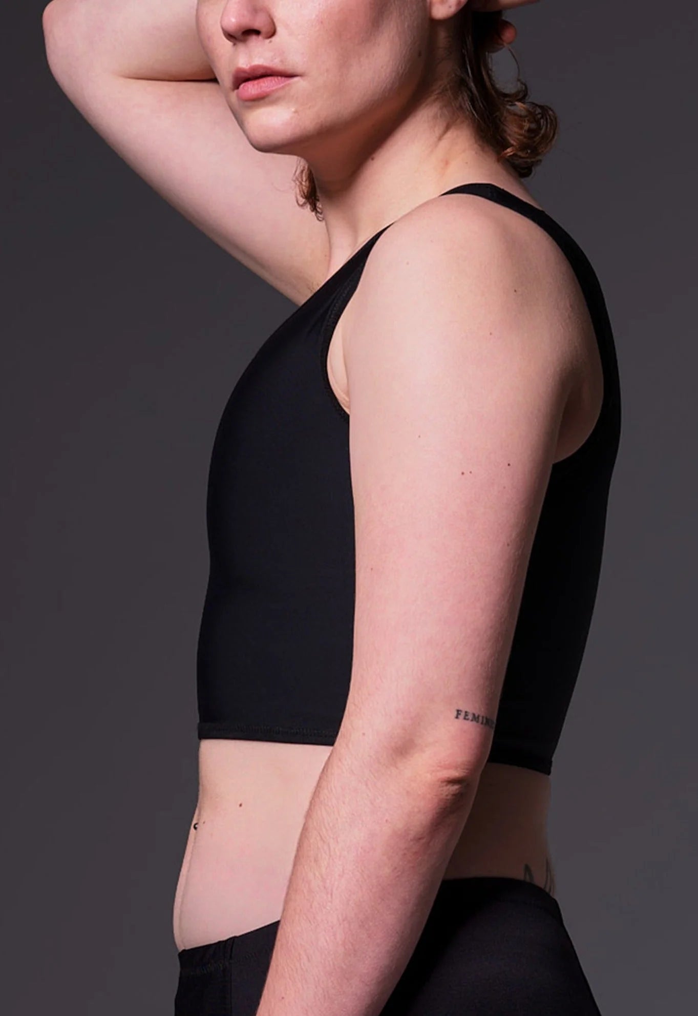 A black cropped chest binder featuring hidden seams, a simple round neckline, and a comfortable compression design.